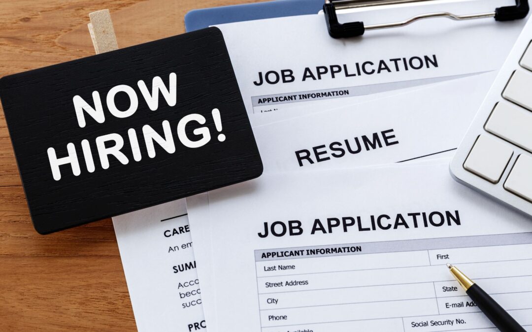 Image of job applications with now hiring sign