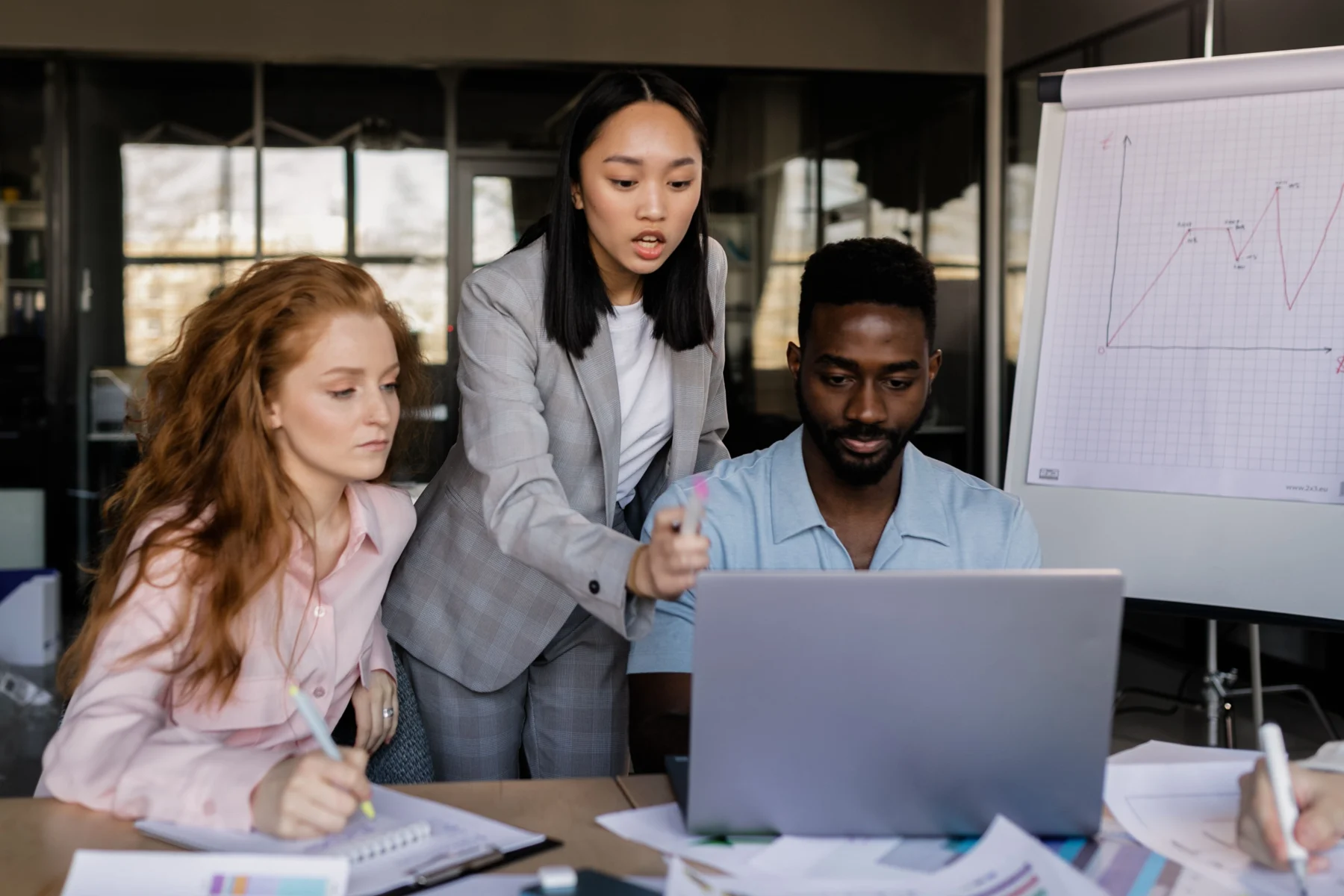Professionals collaborating around a laptop during a business meeting